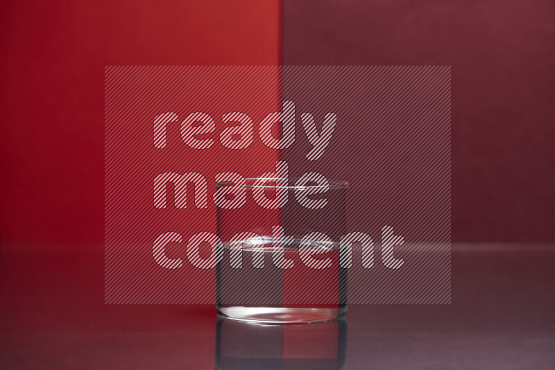 The image features a clear glassware filled with water, set against red and dark red background