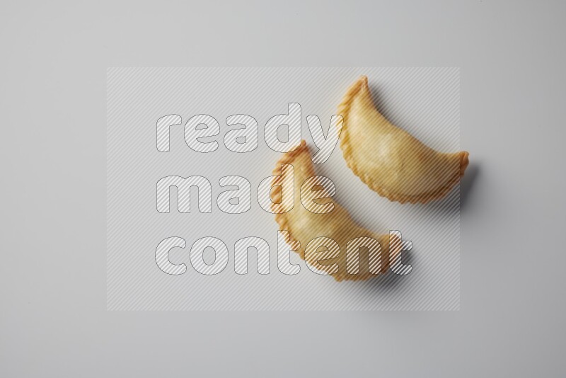 Two fried sambosa from a top angle on a white background