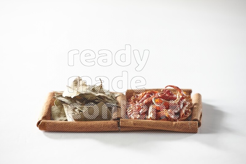 2 squares of cinnamon sticks full of dried red chilis and bay laurel leaves on white flooring