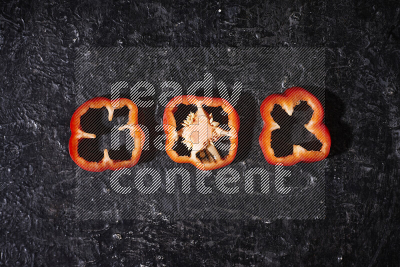 Red bell pepper slices on black background