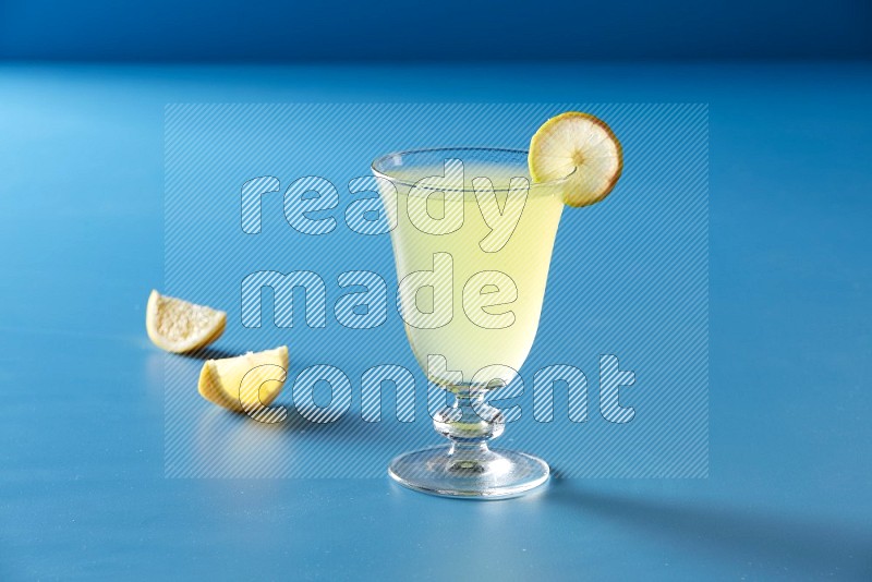 glass of lemon juice with lemon slice  on blue background