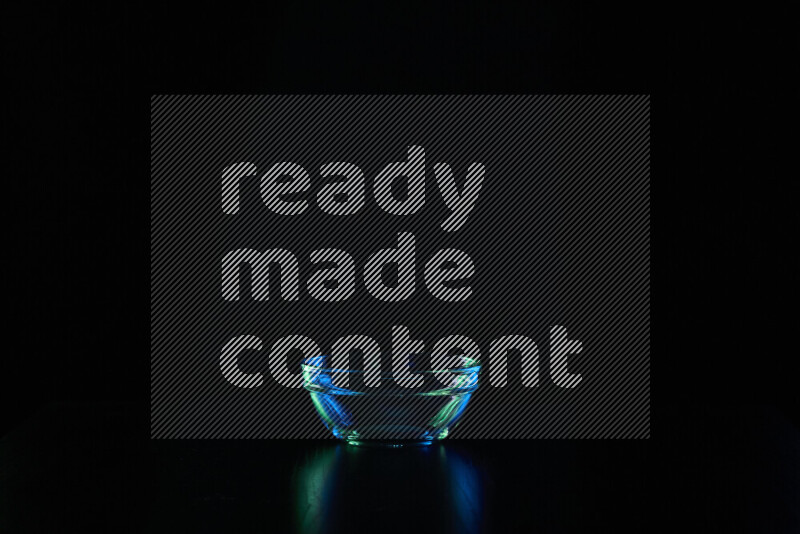 Glassware with rim light in blue and green against black background