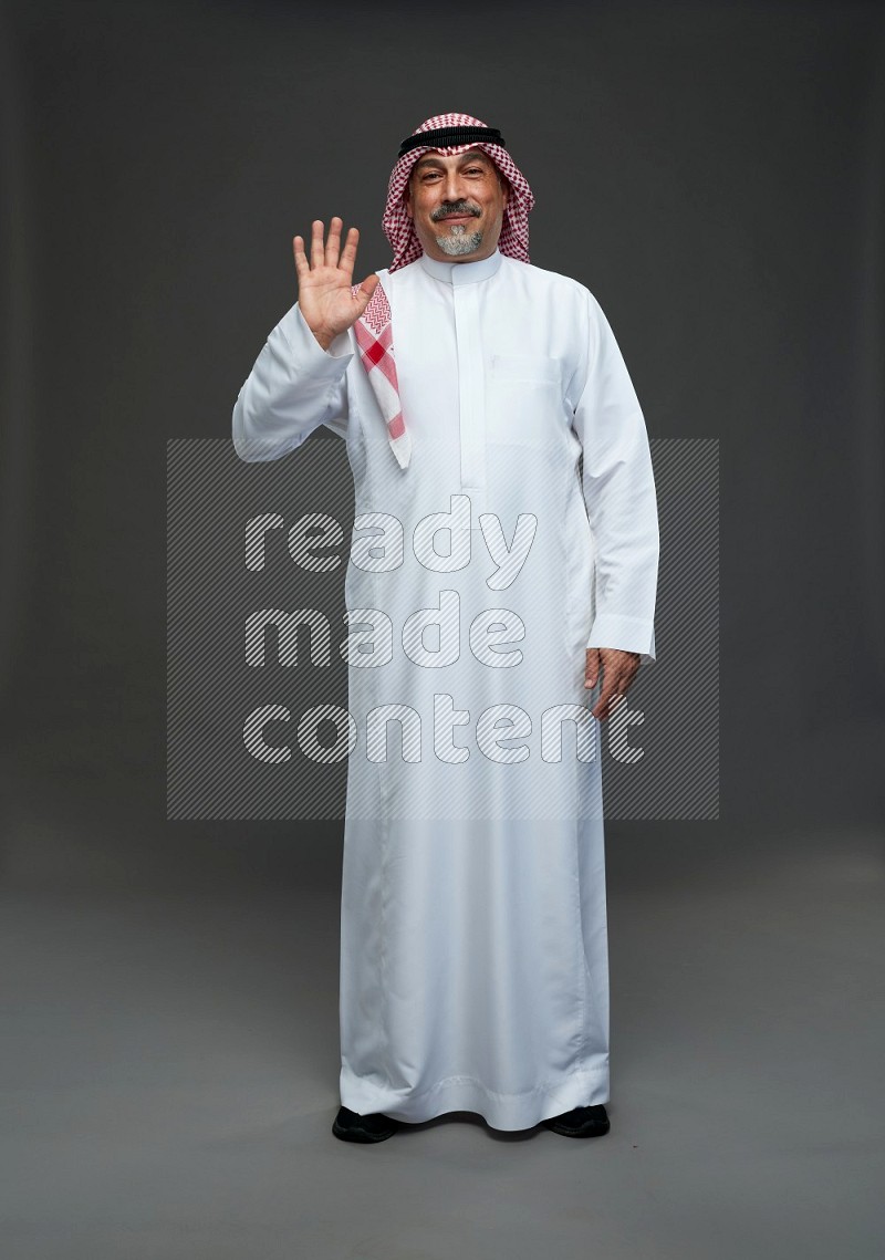 Saudi man with shomag Standing Interacting with the camera on gray background