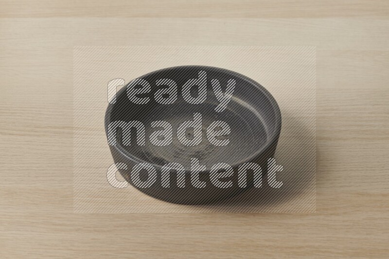 A black pottery oven plate on light wooden background