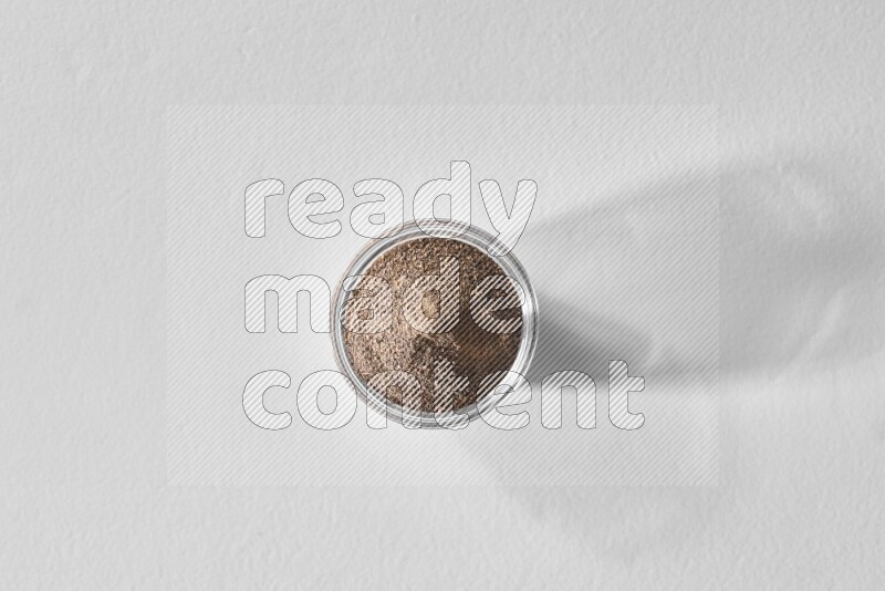 فلفل أسود مطحون في وعاء زجاجي علي خلفية بيضاء