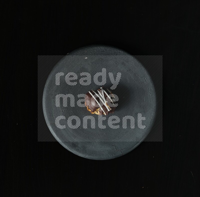 Assorted desserts in a black pottery plate on black background