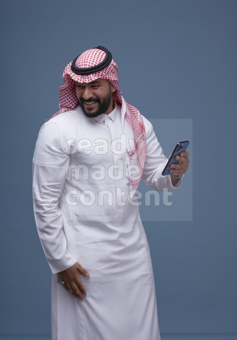 A man Texting on Blue Background wearing Saudi Thob and Shomag