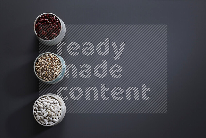 Legumes in pottery bowls on grey background