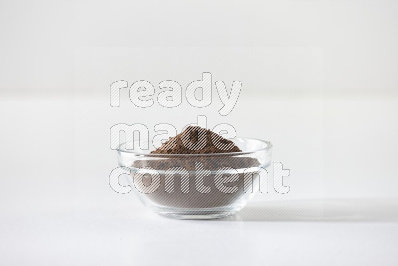 A glass bowl full of cloves powder on white flooring