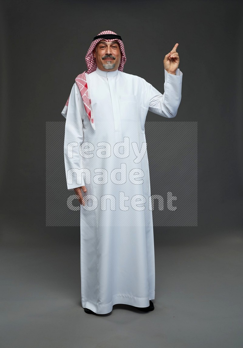 Saudi man with shomag Standing Interacting with the camera on gray background