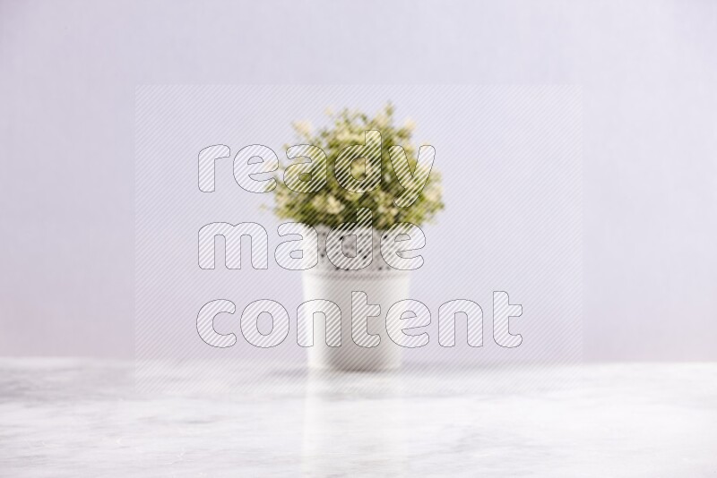 Artificial plant in white decorative pot on grey marble background