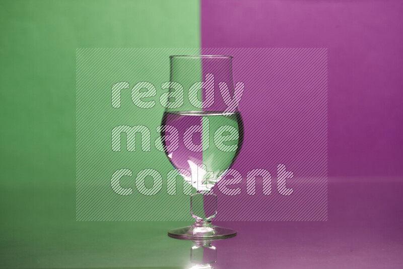 The image features a clear glassware filled with water, set against green and purple background