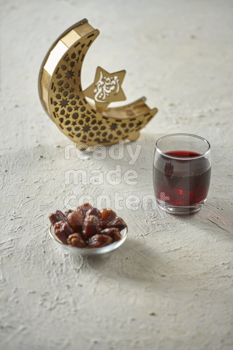A wooden golden crescent lantern with different drinks, dates, nuts, prayer beads and quran on white background