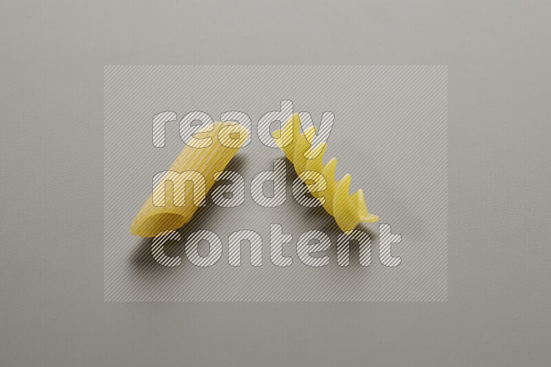 Penne pasta with other types of pasta on grey background