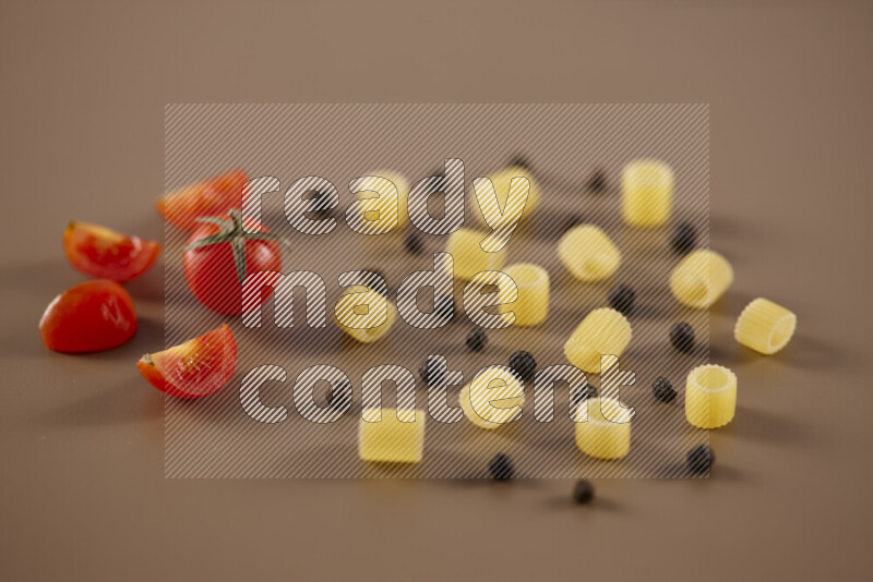 Raw pasta with different ingredients such as cherry tomatoes, garlic, onions, red chilis, black pepper, white pepper, bay laurel leaves, rosemary and cardamom on beige background