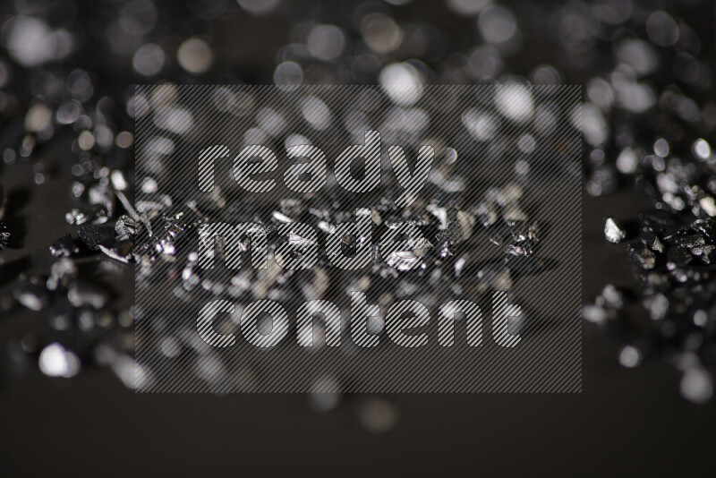 Black shimmering fragments of glass scattered on a black background