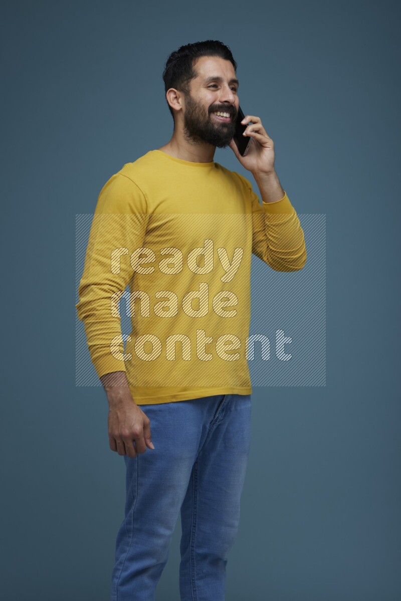 A man having a calling in a blue background wearing a yellow shirt