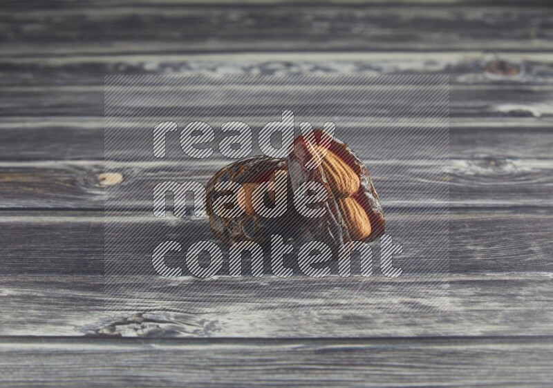 two almond stuffed madjoul dates on a wooden grey background