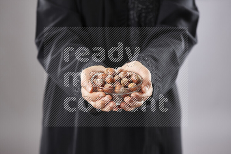 Woman in abaya holding different kinds of nuts in different positions