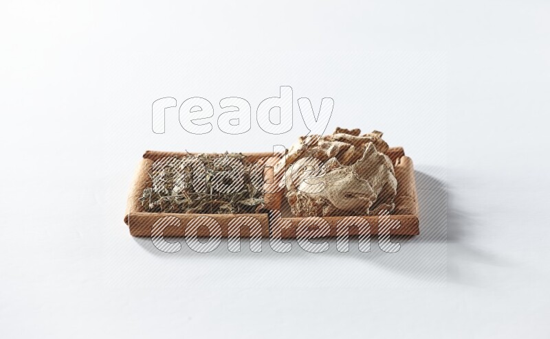 مربعان من أعواد القرفة ممتلئان بالزنجبيل المجفف والريحان المجفف علي خلفية بيضاء