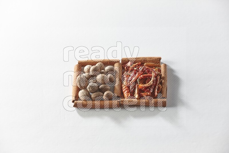 مربعان من أعواد القرفة ممتلئان بالفلفل الحار المجفف وجوزة الطيب علي خلفية بيضاء