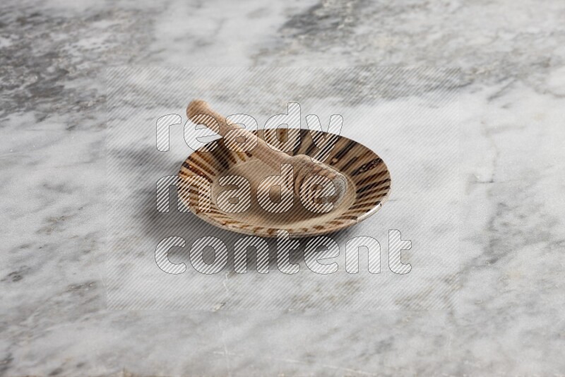 Multicolored pottery plate with wooden honey dipper in it on grey marble background