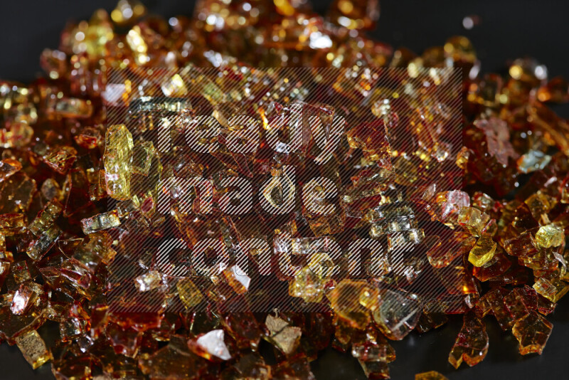 قطع زجاج برتقالية شفافة متناثرة على خلفية سوداء