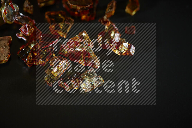 Transparent orange fragments of glass scattered on a black background