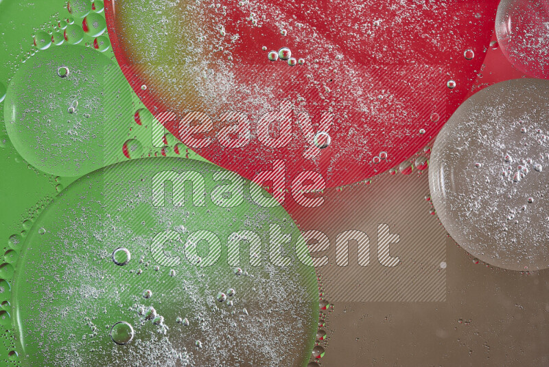 لقطات مقربة لفقاعات من الزيت على سطح الماء باللون البني والأخضر والأحمر