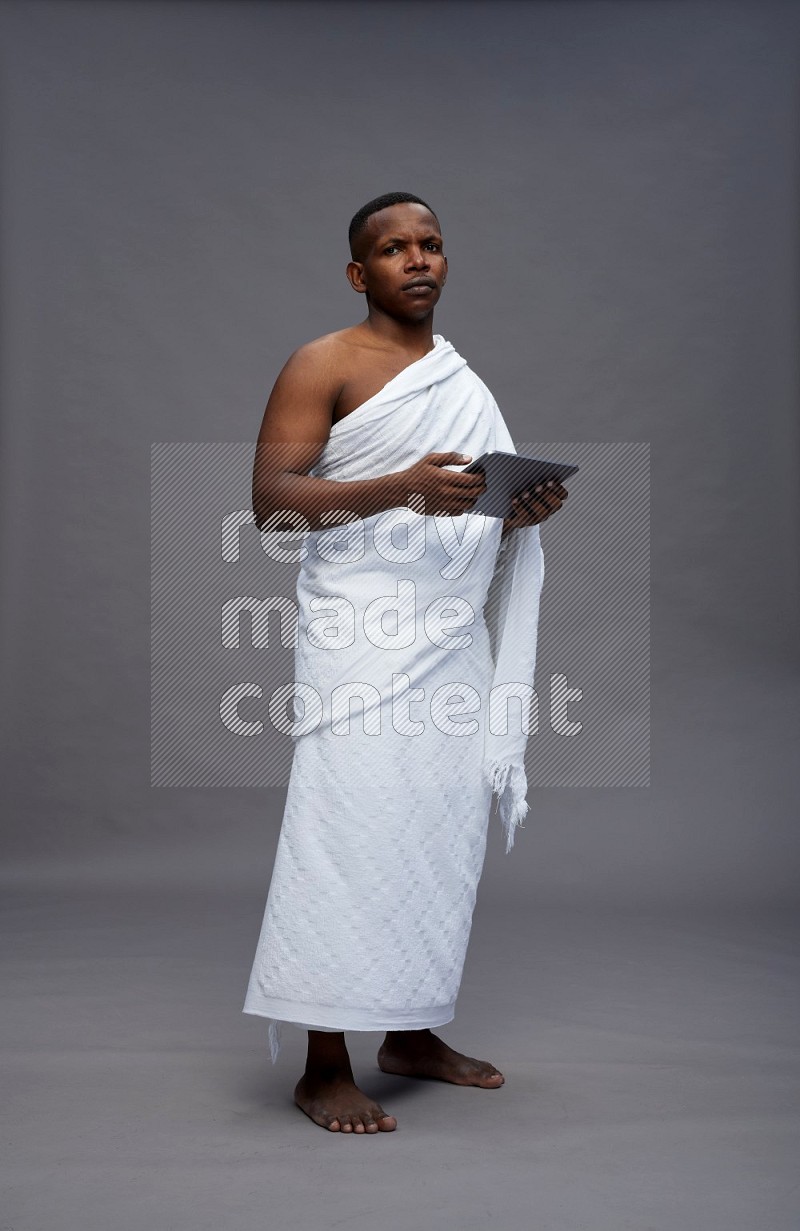 A man wearing Ehram Standing working on tablet on gray background