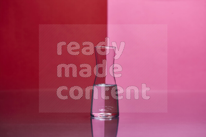 The image features a clear glassware filled with water, set against red and pink background