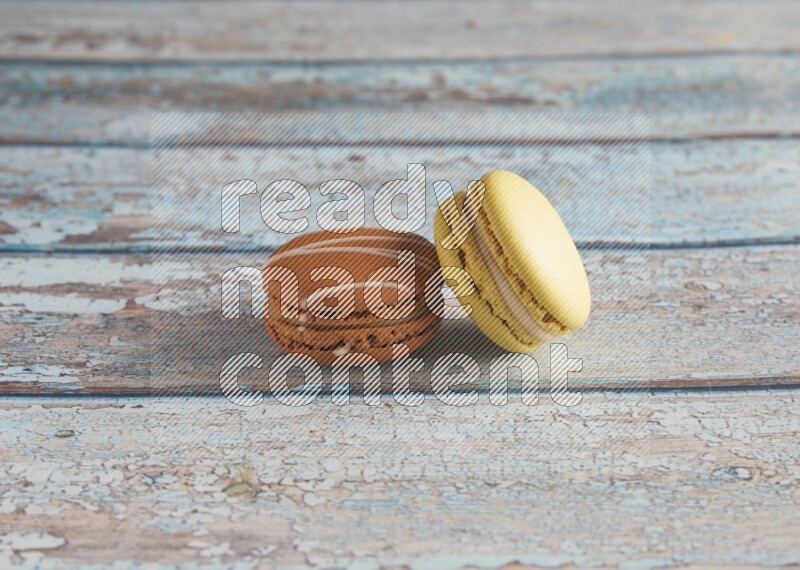 45º Shot of of two assorted Brown Irish Cream, and Yellow Lime macarons on light blue background