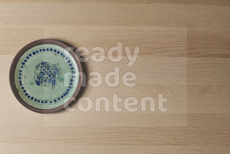 A decorative pottery plate on light wooden background