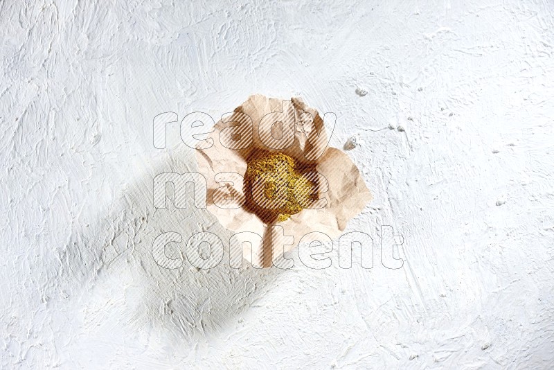 Turmeric powder in a crumpled piece of paper on textured white flooring