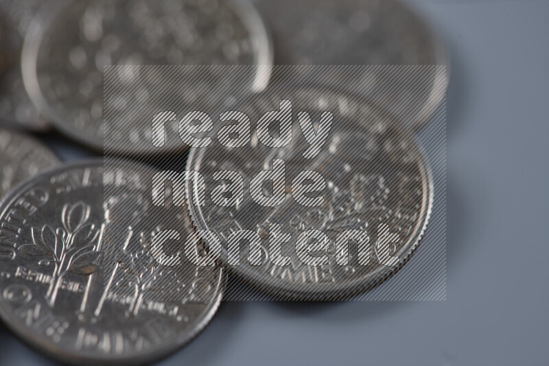 A close-up of scattered United States one dime coins on grey background