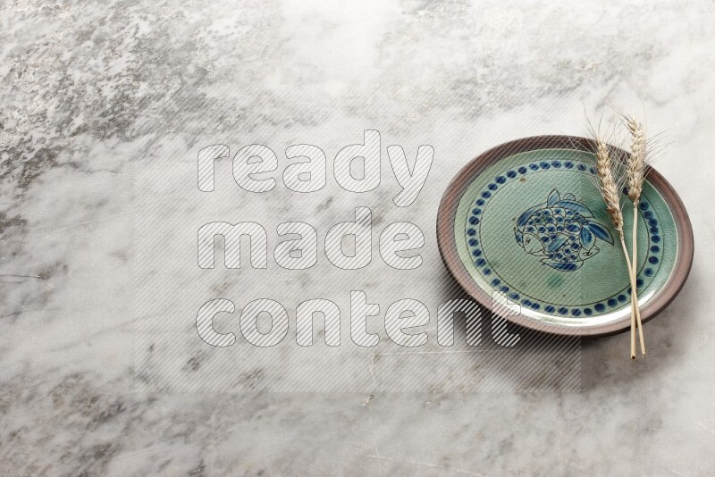 Wheat stalks on decorative pottery plate on grey marble background