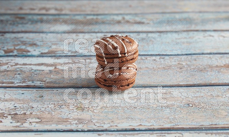 45º Shot of two Brown white  Chocolate Caramel macarons on light blue wooden background