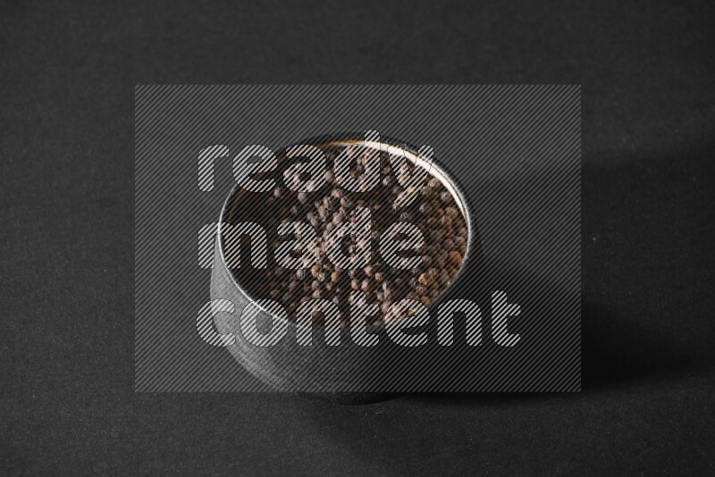 حبوب الفلفل الأسود في وعاء فخاري أسود علي خلفية سوداء