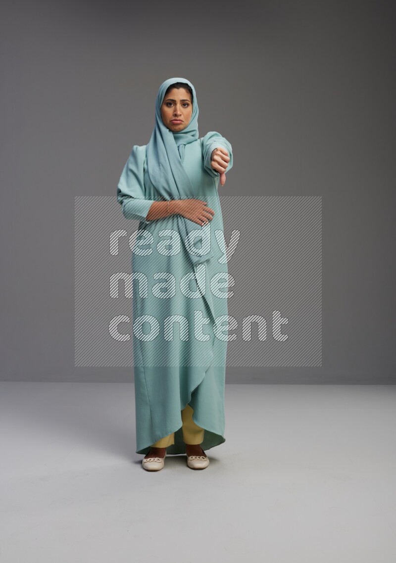 Saudi Woman wearing Abaya standing interacting with the camera on Gray background