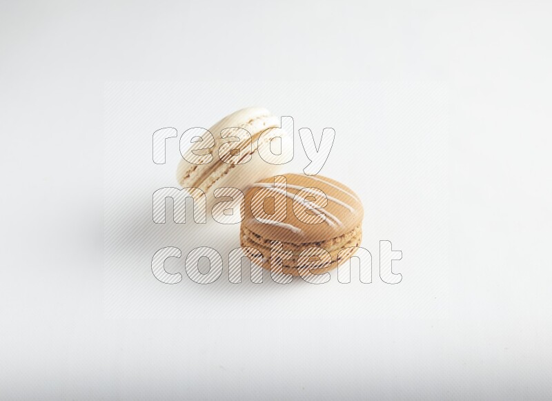 45º Shot of of two assorted Brown Irish Cream, and White Caramel fleur de sel macarons on white background