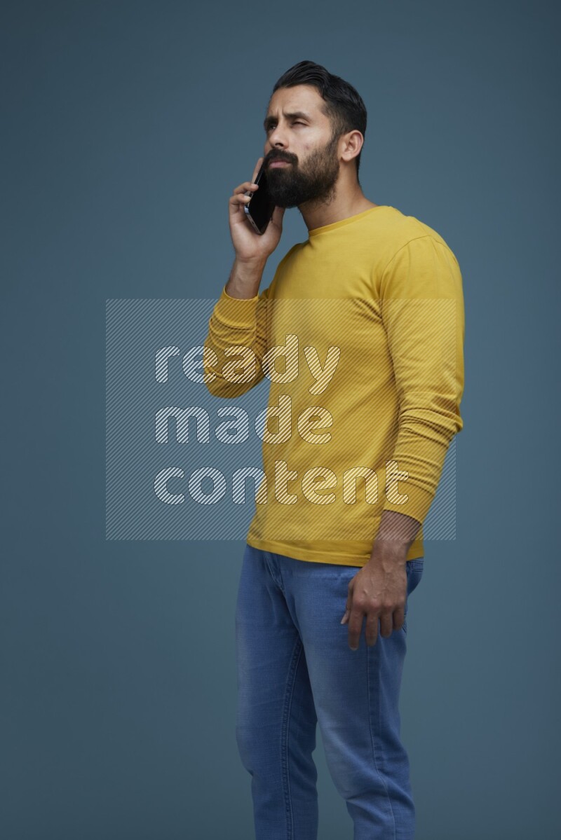 A man having a calling in a blue background wearing a yellow shirt