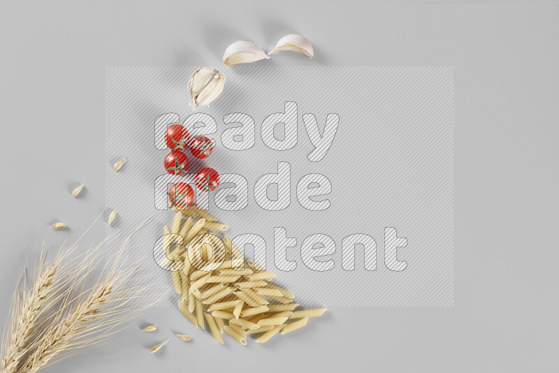 Mini penne with garlic, cherry tomatoes and wheat stalks on light grey background