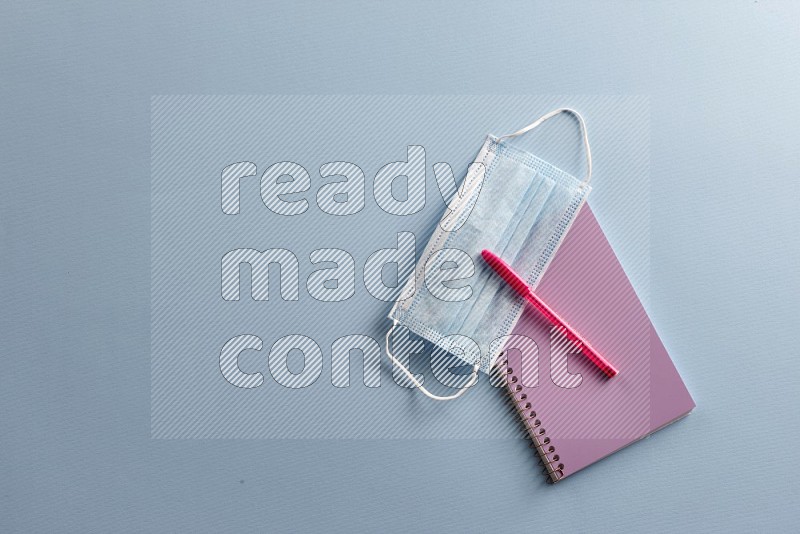 A purple notebook with school supplies on blue background (Back to school)