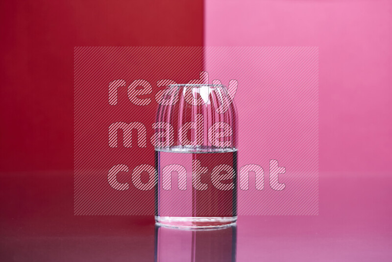 The image features a clear glassware filled with water, set against red and pink background