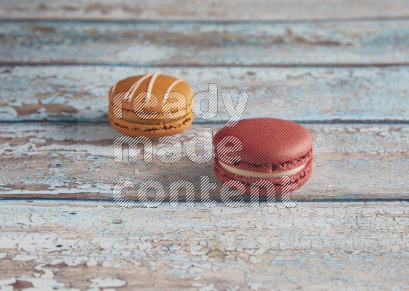 45º Shot of of two assorted Brown Irish Cream, and Red Velvet macarons on light blue background