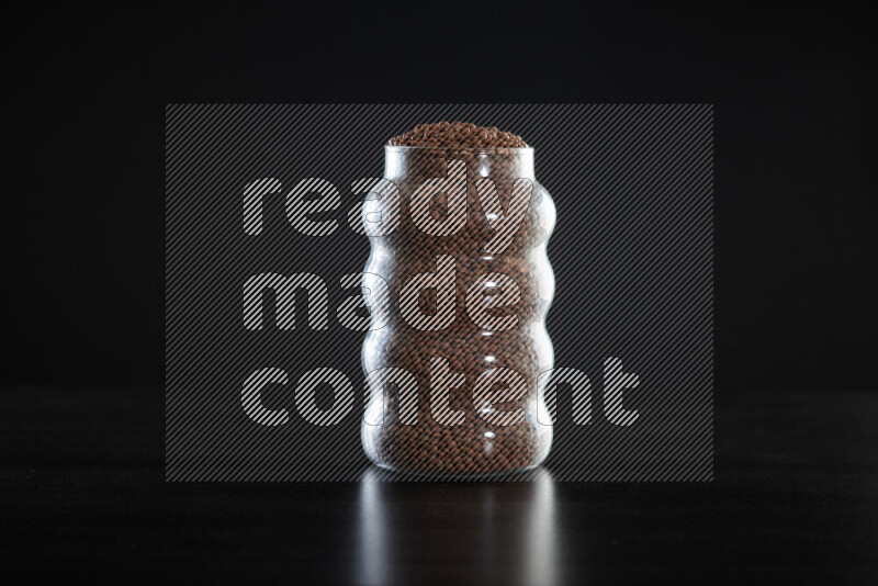 Brown lentils in a glass jar on black background