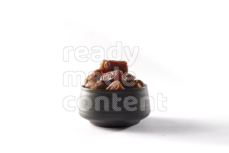 Dates in a black pottery bowl on white background