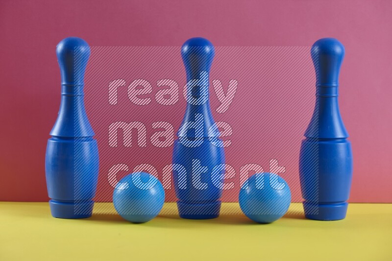 Plastic bowling pins with balls on pink and yellow background (kids toys)