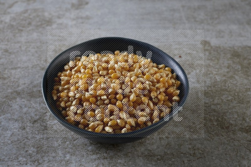 corn kernel in a black ceramic bowl on a grey textured countertop