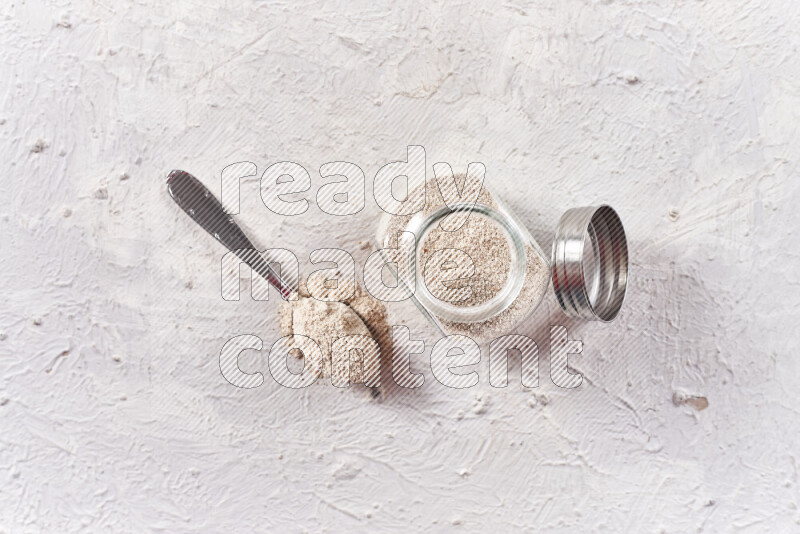 A glass jar full of onion powder on white background